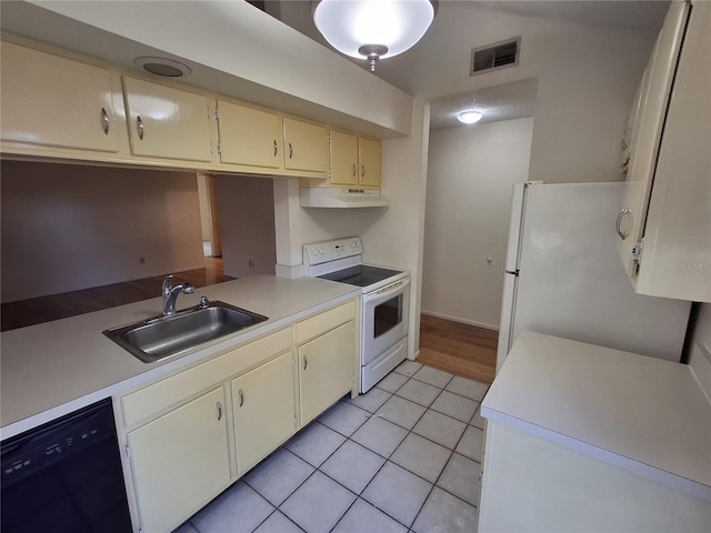 kitchen featuring light tile patterned flooring, cream cabinetry, sink, and white appliances