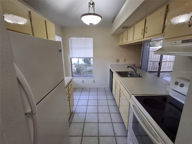 kitchen featuring hanging light fixtures, light tile patterned floors, cream cabinetry, sink, and white appliances