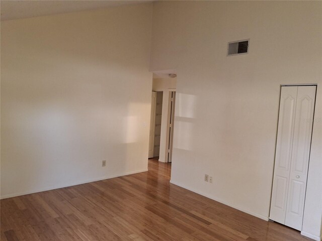 unfurnished room featuring hardwood / wood-style flooring and a towering ceiling