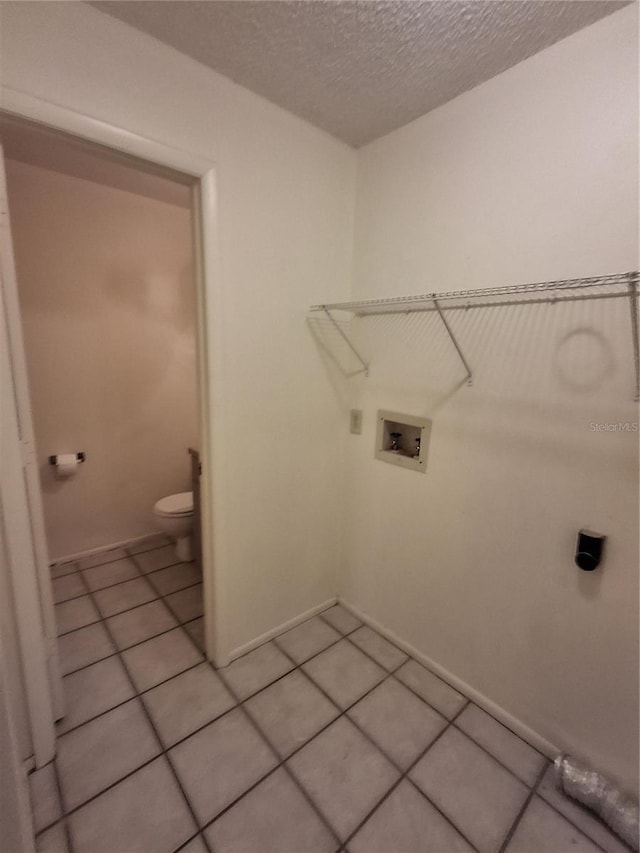 laundry area featuring hookup for a washing machine, a textured ceiling, and light tile patterned floors