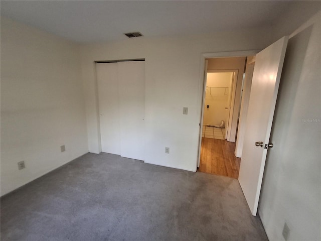 unfurnished bedroom featuring a closet and dark colored carpet