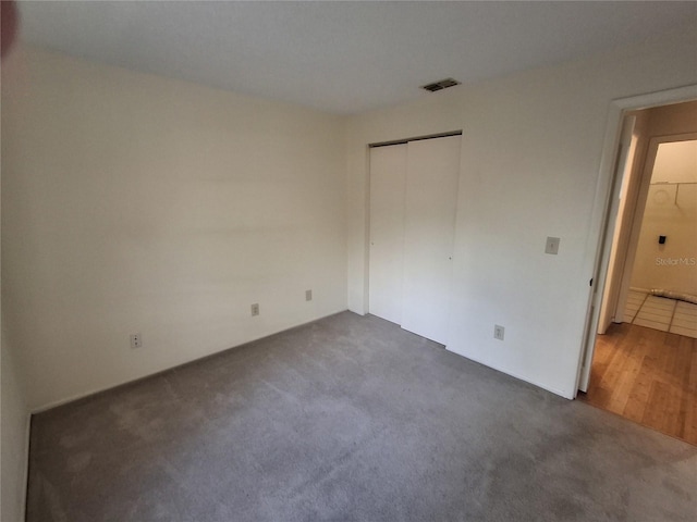 unfurnished bedroom with a closet and dark carpet