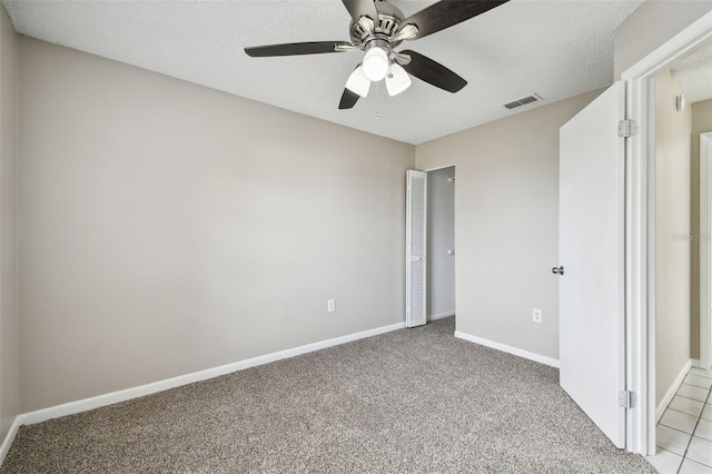 unfurnished bedroom with a textured ceiling, light colored carpet, and ceiling fan