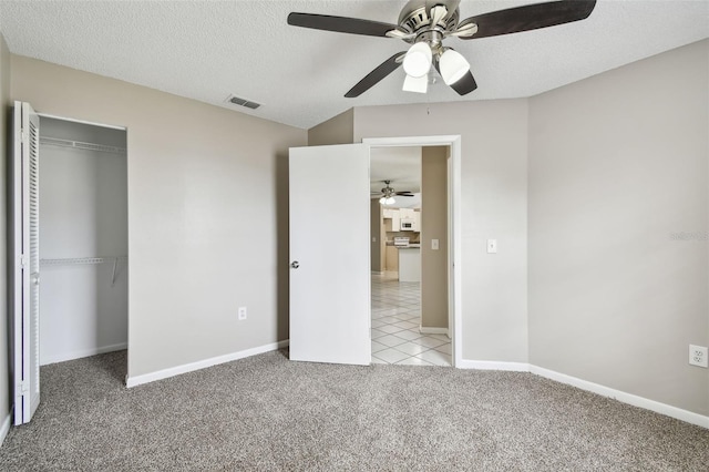 unfurnished bedroom with a closet, a textured ceiling, light carpet, and ceiling fan