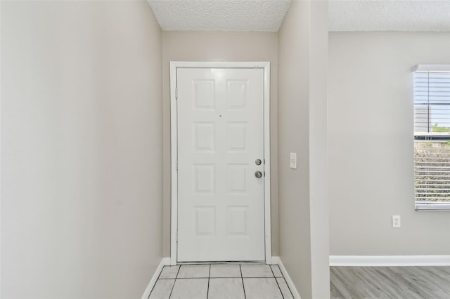 doorway with light hardwood / wood-style flooring and a textured ceiling