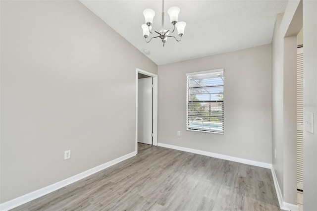 unfurnished bedroom with a chandelier, lofted ceiling, a textured ceiling, and light hardwood / wood-style flooring