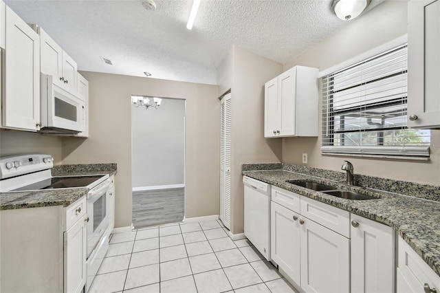 kitchen featuring a textured ceiling, sink, white cabinets, dark stone countertops, and white appliances