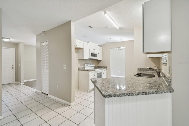 kitchen featuring white cabinets, kitchen peninsula, a textured ceiling, sink, and white appliances