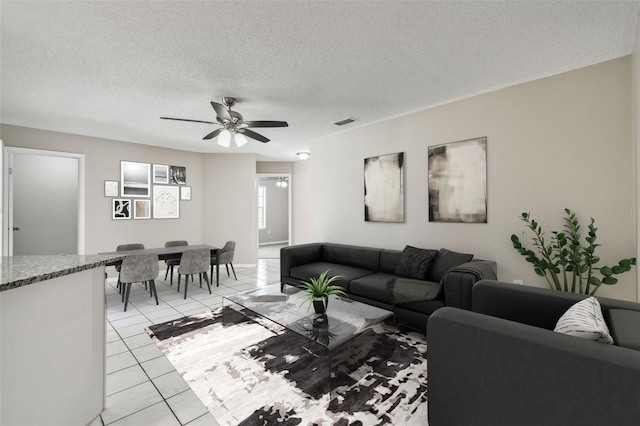 living room featuring light tile patterned flooring, ceiling fan, and a textured ceiling