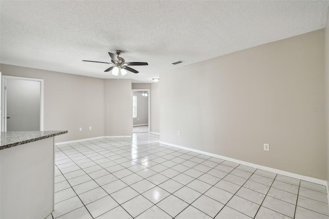 unfurnished room with a textured ceiling, ceiling fan, and light tile patterned floors