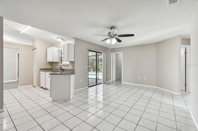 kitchen with white dishwasher, dark stone counters, ceiling fan, a textured ceiling, and white cabinets