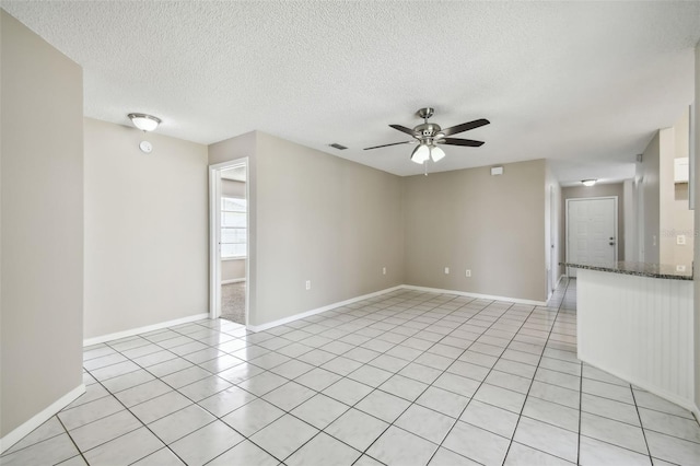 empty room featuring a textured ceiling, ceiling fan, and light tile patterned floors