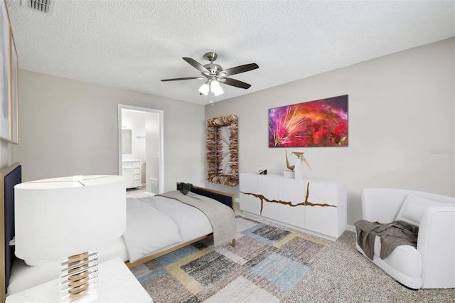 bedroom featuring ensuite bathroom, carpet flooring, a textured ceiling, and ceiling fan