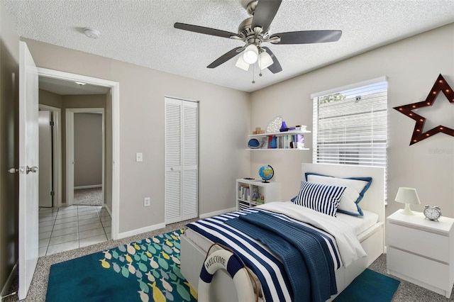 tiled bedroom with a textured ceiling, ceiling fan, and a closet