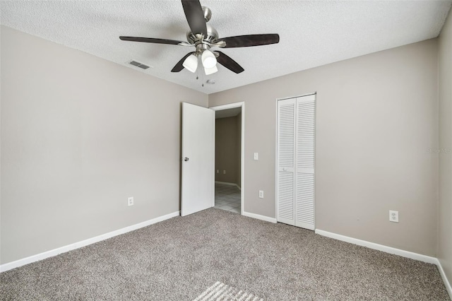 unfurnished bedroom with a textured ceiling, carpet flooring, ceiling fan, and a closet