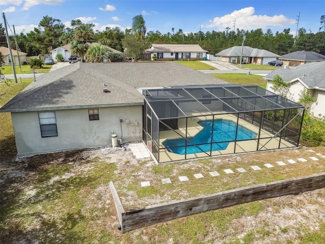 rear view of property featuring glass enclosure and a patio