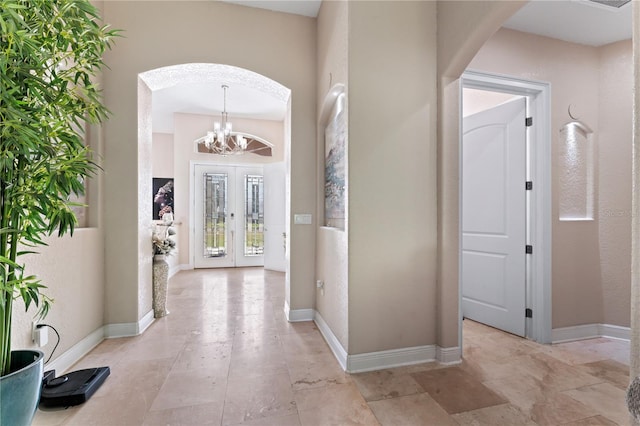 foyer with french doors and an inviting chandelier