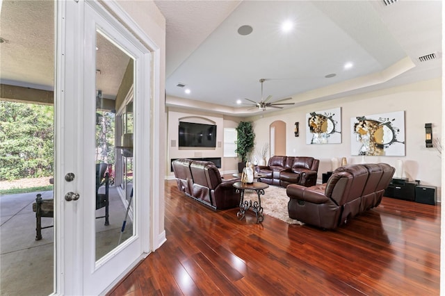 living room with ceiling fan, a textured ceiling, and dark hardwood / wood-style floors