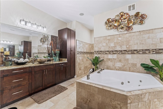 bathroom featuring tiled bath, tile patterned flooring, tile walls, and vanity