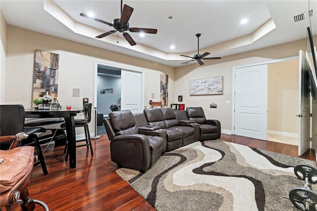 living room featuring ceiling fan, dark hardwood / wood-style floors, and a raised ceiling