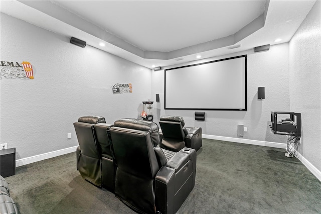 home theater room with dark carpet and a raised ceiling