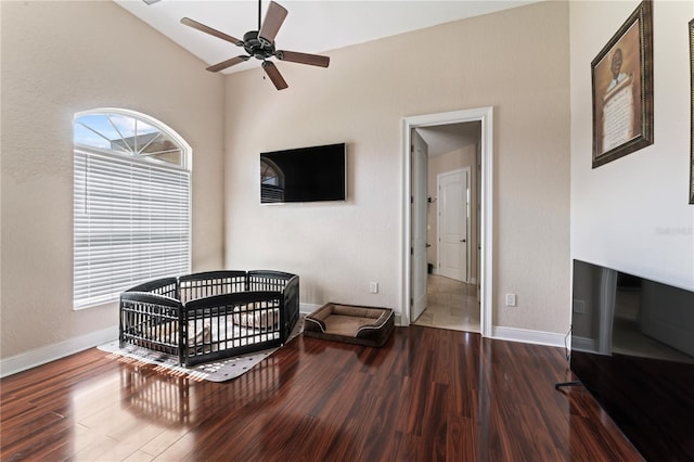 bedroom featuring ceiling fan, a crib, wood-type flooring, and vaulted ceiling