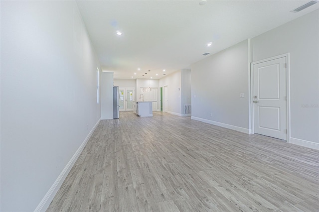 unfurnished living room with light hardwood / wood-style floors and sink