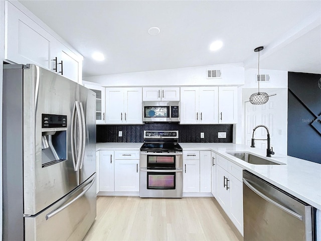 kitchen featuring appliances with stainless steel finishes, backsplash, sink, decorative light fixtures, and white cabinets