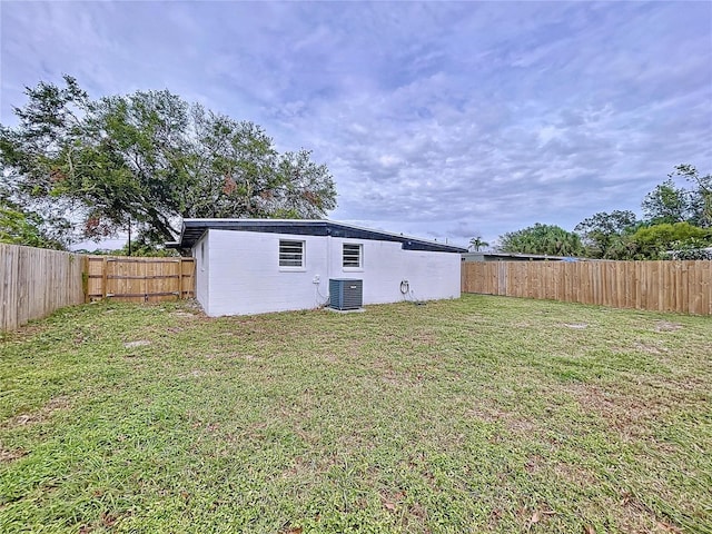 rear view of property featuring a yard and cooling unit