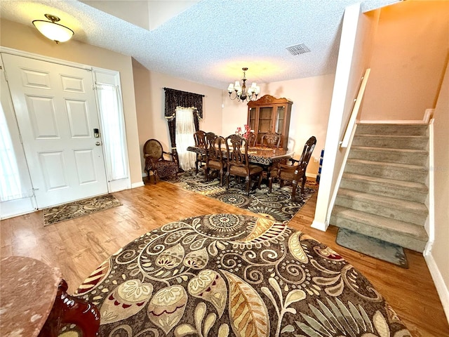 entryway featuring hardwood / wood-style flooring, a textured ceiling, and an inviting chandelier