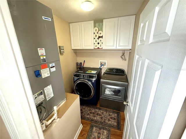 laundry room featuring independent washer and dryer, cabinets, and dark hardwood / wood-style flooring