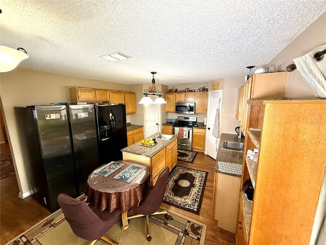 kitchen featuring dark hardwood / wood-style floors, stainless steel appliances, sink, decorative light fixtures, and a textured ceiling