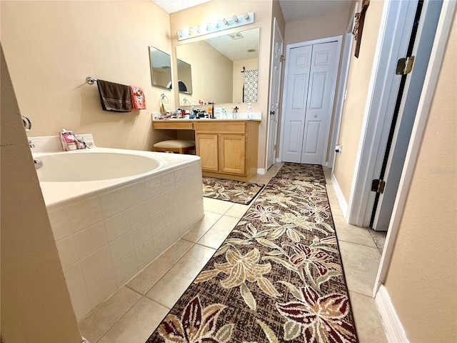 bathroom with vanity, a tub, tile patterned floors, and a textured ceiling