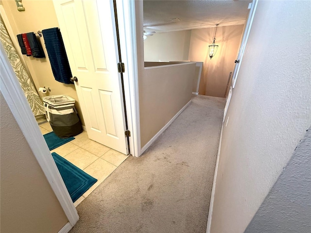 hallway featuring light carpet and a textured ceiling