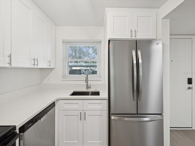 kitchen featuring white cabinets, sink, stainless steel appliances, and a textured ceiling