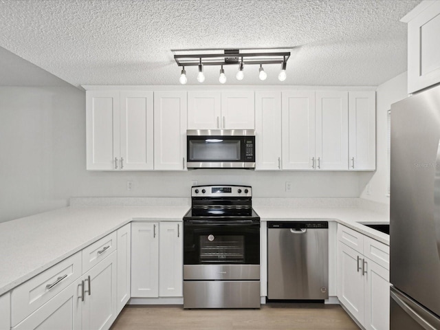 kitchen with light hardwood / wood-style floors, white cabinetry, track lighting, a textured ceiling, and stainless steel appliances