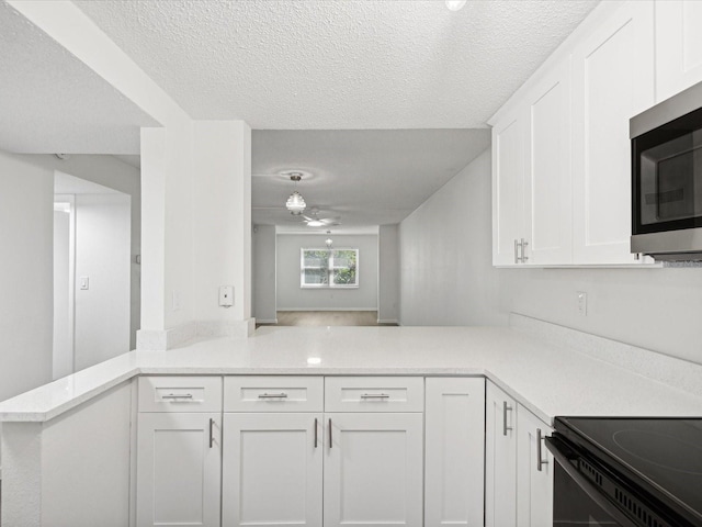 kitchen featuring a textured ceiling, kitchen peninsula, and white cabinets