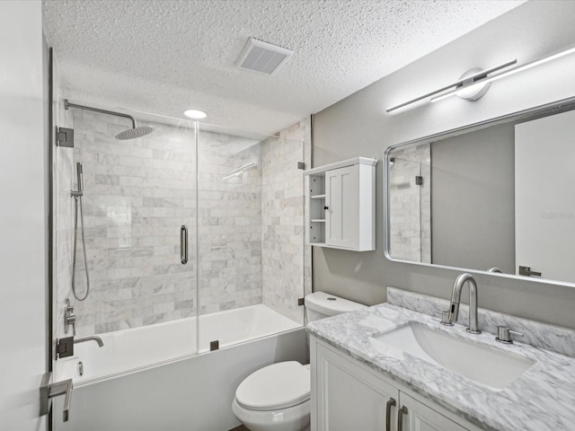 full bathroom with a textured ceiling, shower / bath combination with glass door, vanity, and toilet