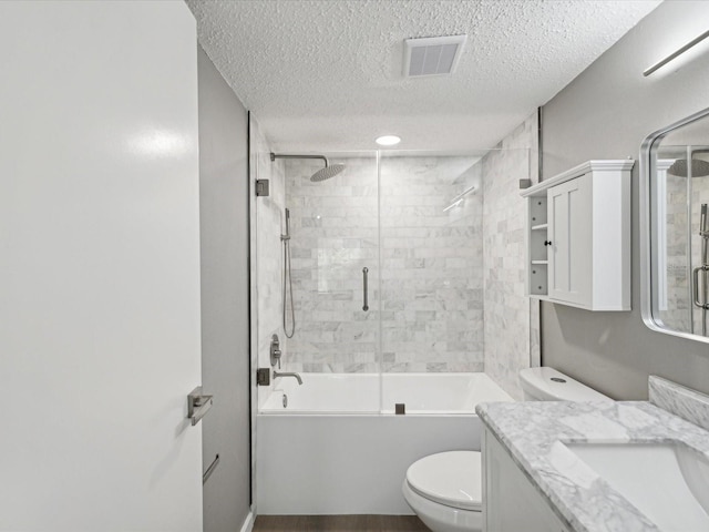 full bathroom with a textured ceiling, combined bath / shower with glass door, toilet, and vanity