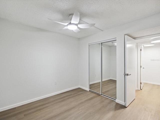 unfurnished bedroom with ceiling fan, a textured ceiling, a closet, and light hardwood / wood-style flooring