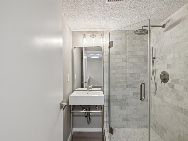 bathroom featuring a shower with shower door and sink