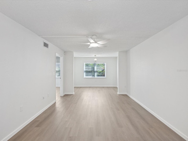 empty room with ceiling fan, light wood-type flooring, and a textured ceiling