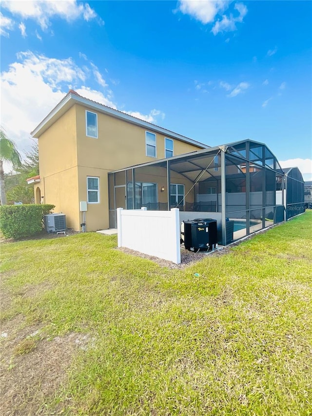 back of property with a lanai, a swimming pool, cooling unit, and a yard