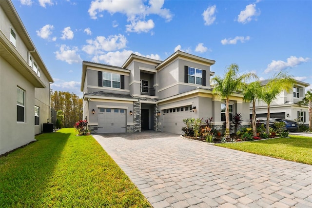 view of front of home with a garage, a front lawn, and central AC