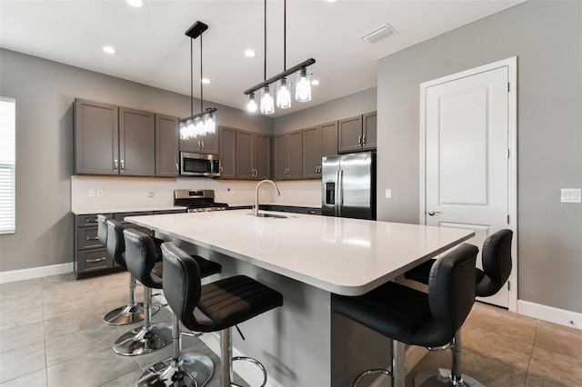 kitchen featuring a kitchen island with sink, a kitchen bar, stainless steel appliances, and sink