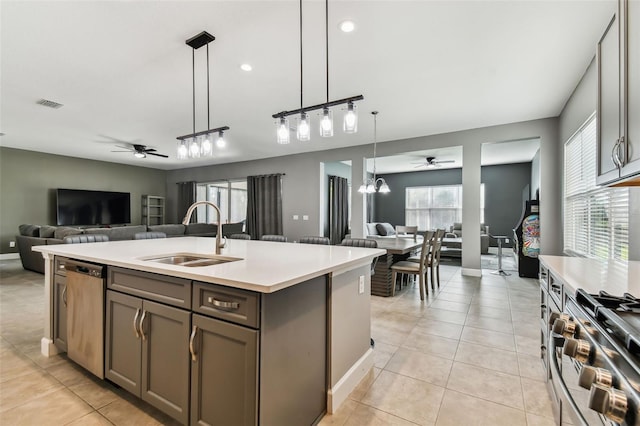 kitchen with stainless steel appliances, light tile patterned flooring, sink, an island with sink, and pendant lighting