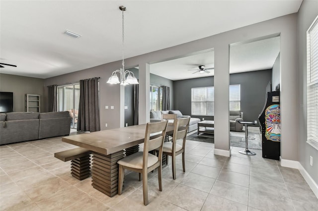 tiled dining room with ceiling fan with notable chandelier