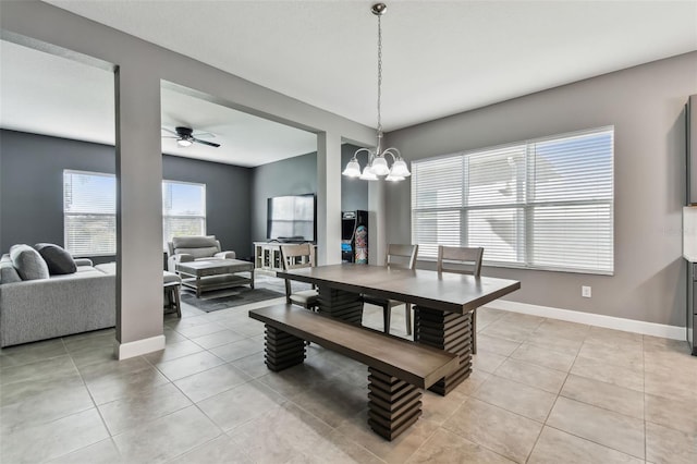 tiled dining room with ceiling fan with notable chandelier