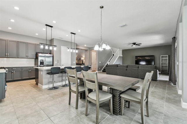 dining space featuring light tile patterned flooring, ceiling fan with notable chandelier, and sink