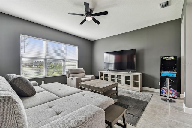 living room featuring a textured ceiling, light tile patterned floors, and ceiling fan